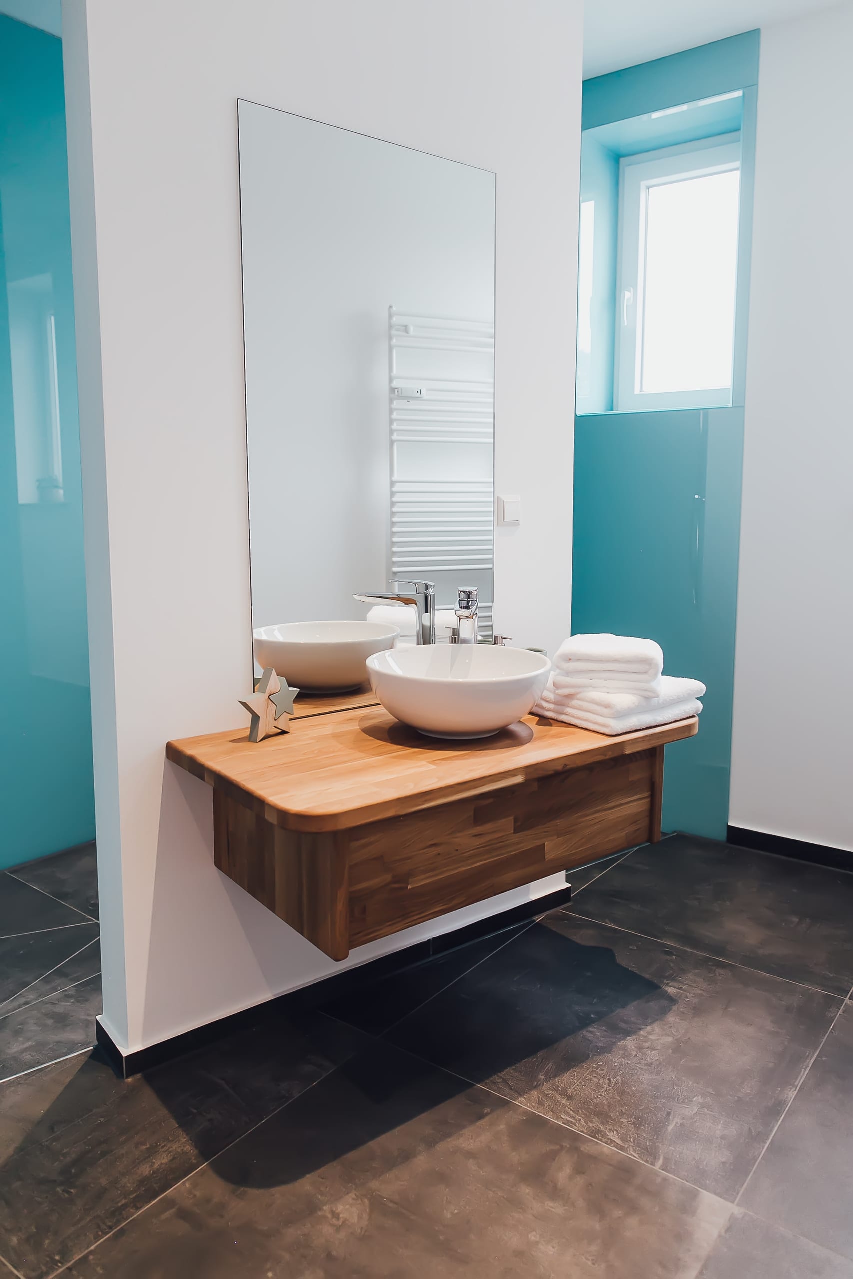 Modernes Badezimmer mit Holztisch, zwei weißen Aufsatzwaschbecken und großem Spiegel