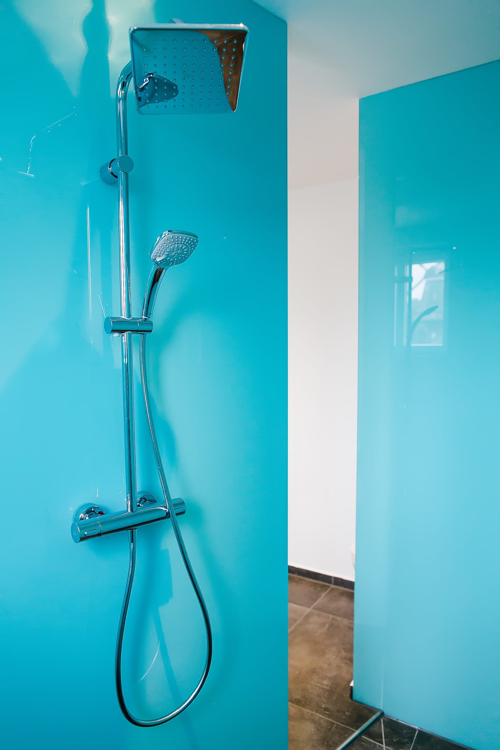 Dusche mit Chromarmatur und feststehendem Duschkopf, türkise Wandverkleidung