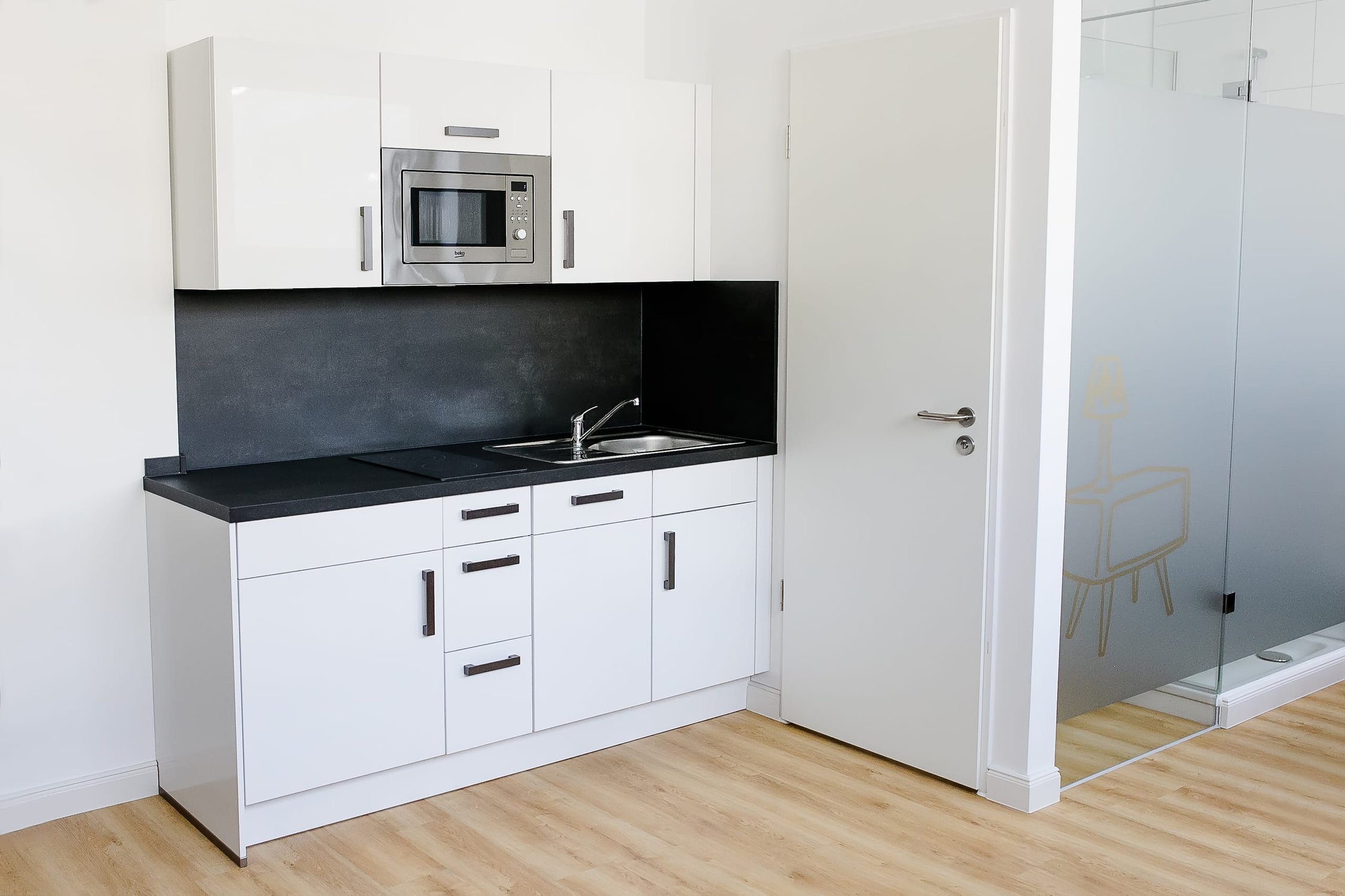 Moderne Pantryküche in Weiß und Schwarz mit Mikrowelle, Spüle, Tür und Glaswand