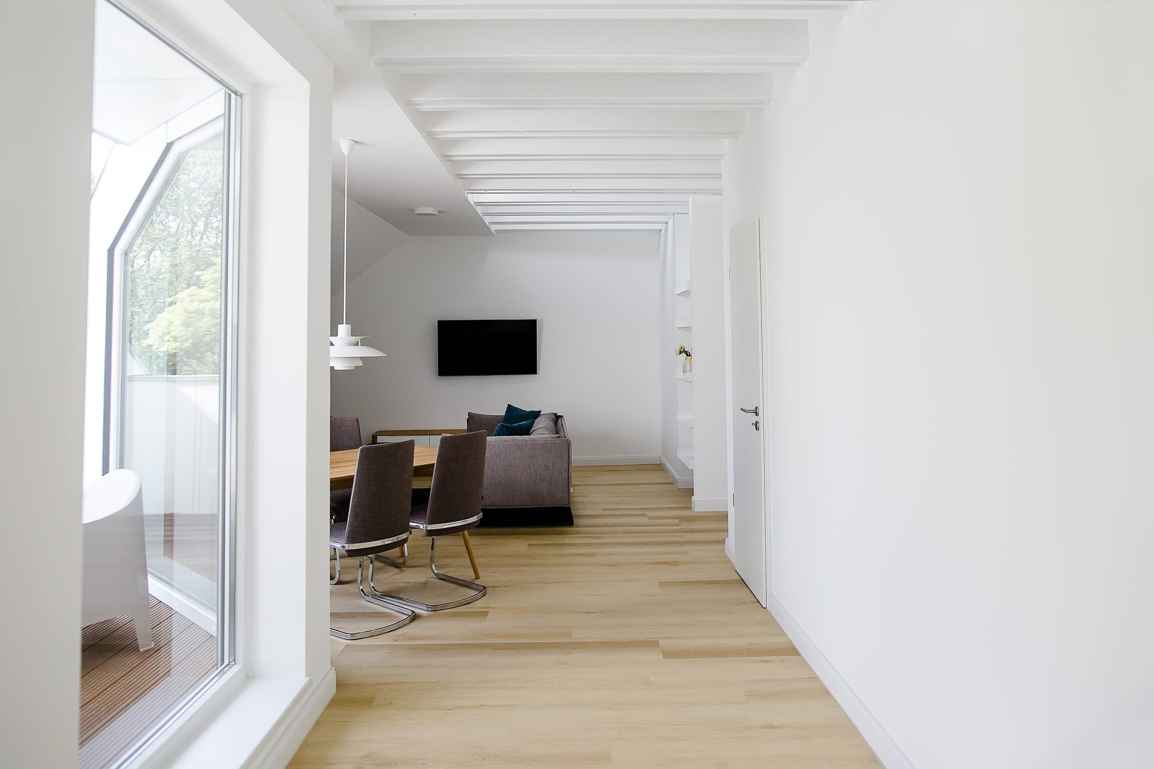 Heller Flur mit Holzboden und offener Sicht auf Wohnzimmer mit Esstisch und Sofa