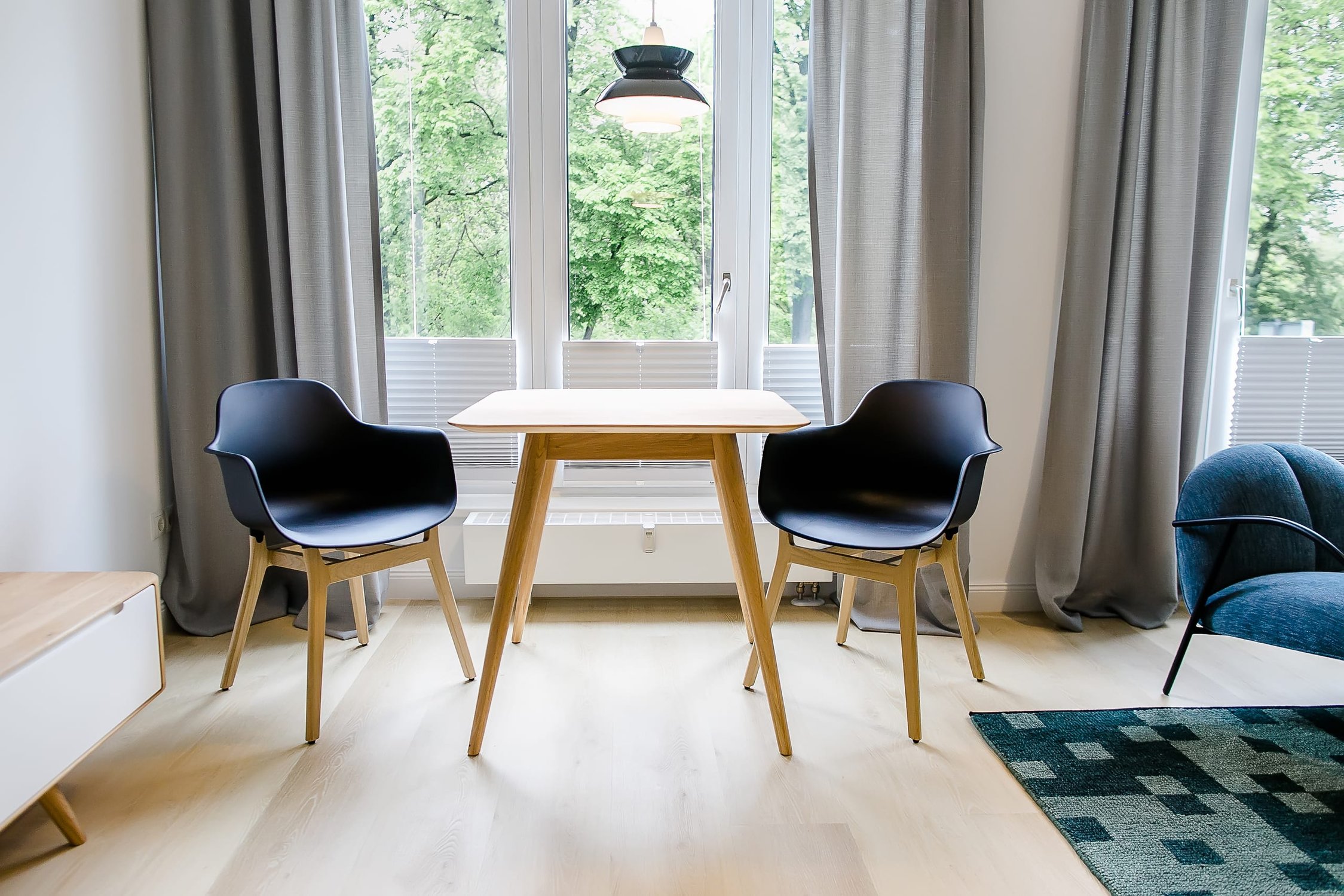 Moderner Essbereich mit Holztisch, schwarzen Stühlen, großen Fenstern und grauen Vorhängen